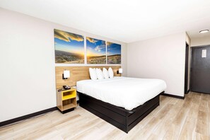 Una habitación de hotel con una cama, una mesita de noche con un teléfono y tres cuadros de paisajes en la pared.
