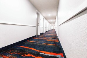 Un pasillo largo y estrecho con paredes blancas y suelo alfombrado.