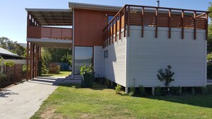 Una casa moderna a due piani con un portico coperto e un giardino recintato.