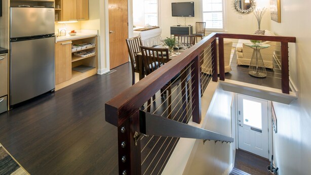 Een moderne keuken met een roestvrijstalen koelkast, houten keukenkastjes en een eethoek met een houten tafel en stoelen.