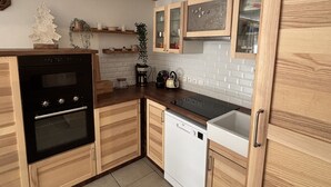 A modern kitchen with wooden cabinets, a black oven, a dishwasher, and a white tiled backsplash.