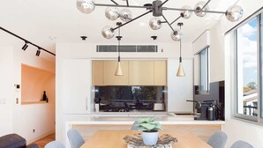 A modern kitchen with a central island, pendant lighting, and a view of the outdoors. - Perfect Located 2-Bed with Spacious Balcony & BBQ (Cremorne)