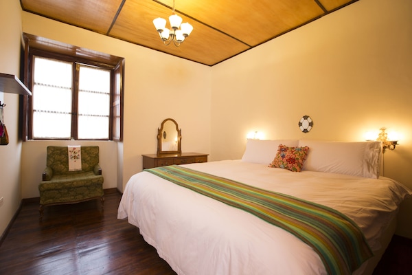 Bedroom 1, with comfortable king size bed, reading chair, and vanity table