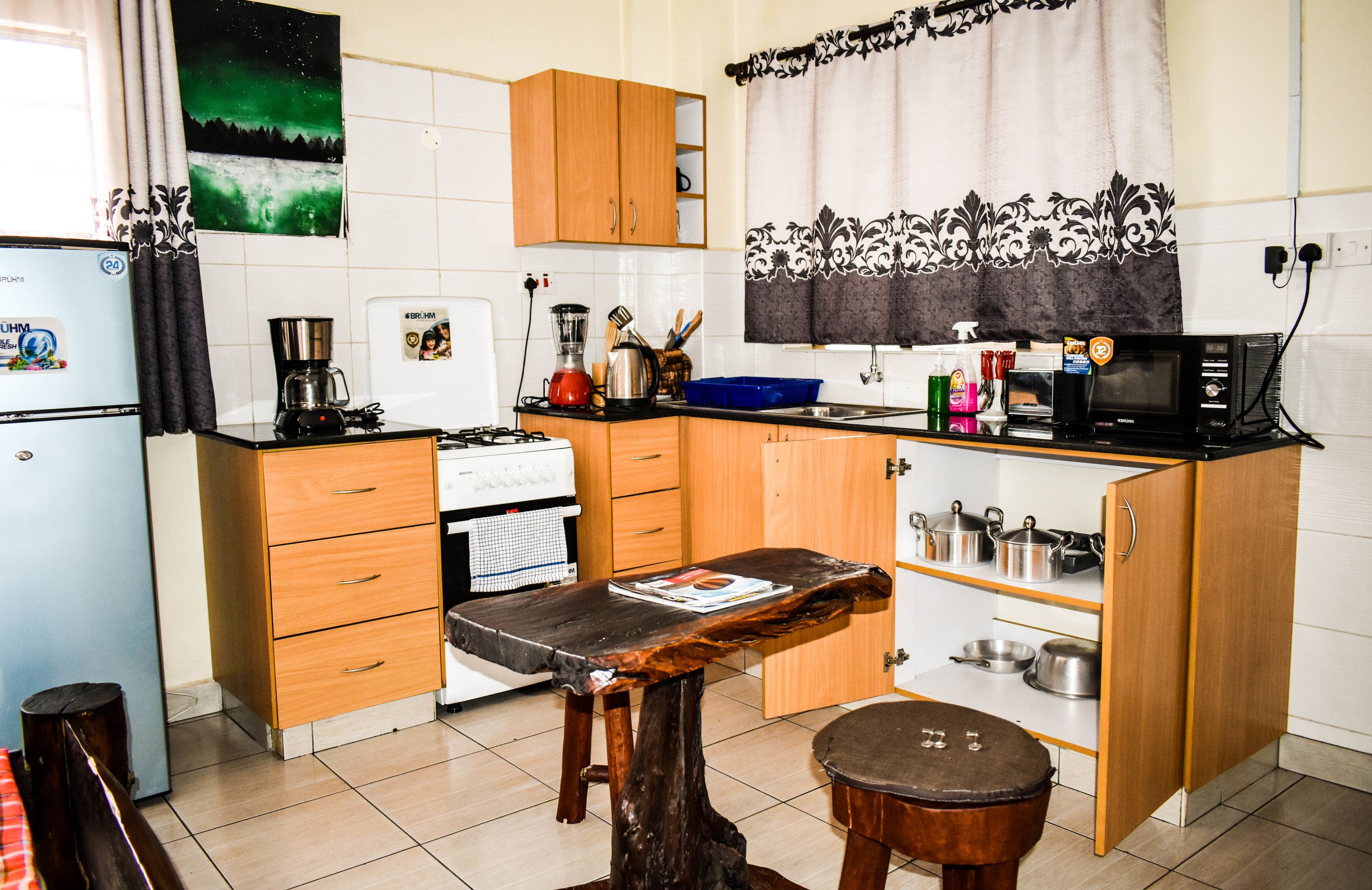 A compact kitchen with wooden cabinets, a refrigerator, a stove, and a microwave.