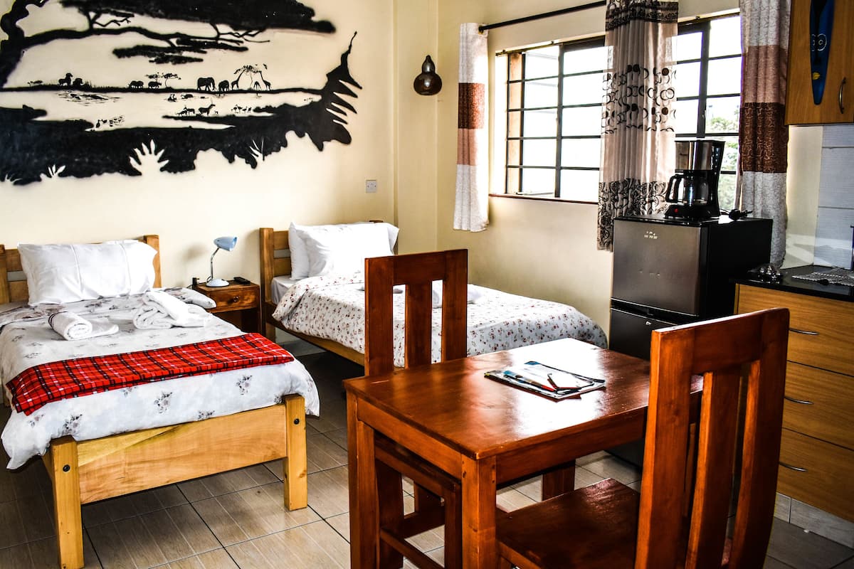Une chambre avec deux lits, une table en bois et un réfrigérateur.