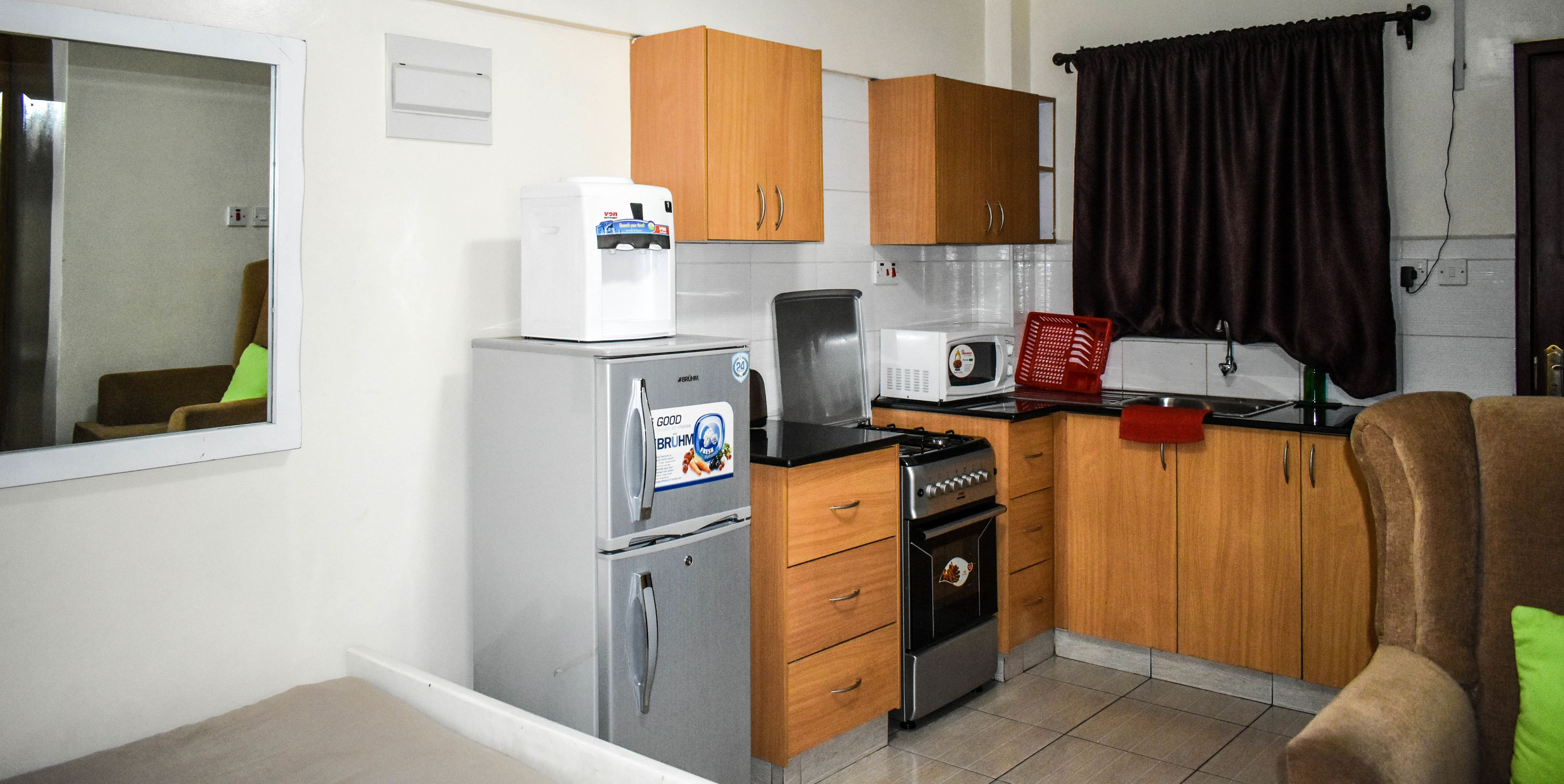 A compact kitchen with a refrigerator, microwave, stove, and wooden cabinets.