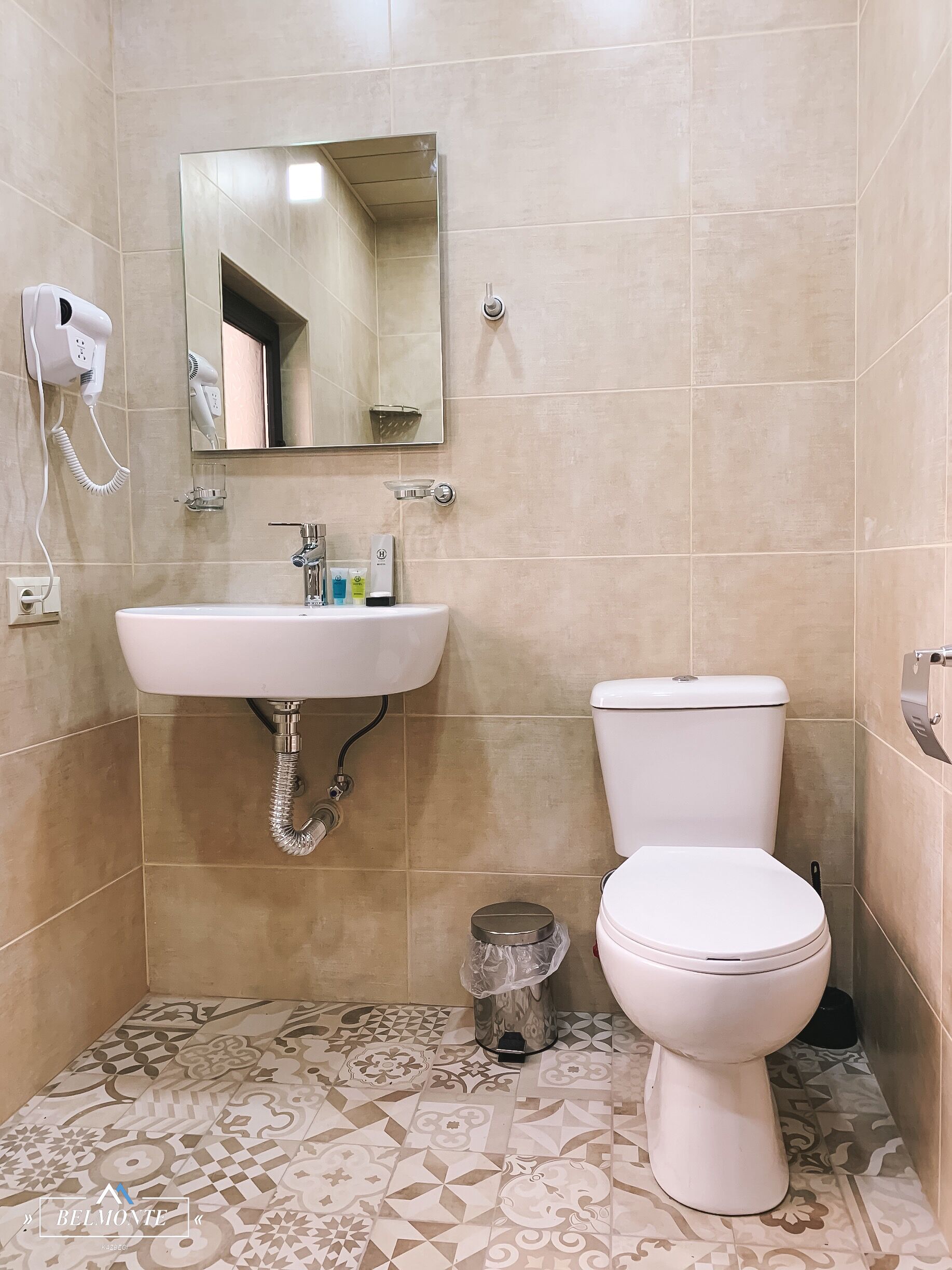 A bathroom with a white sink, a toilet, and a mirror above the sink.
