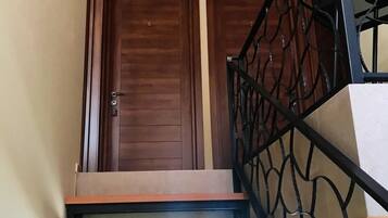 Una escalera de madera con barandilla metálica que conduce a una puerta con el número 6.