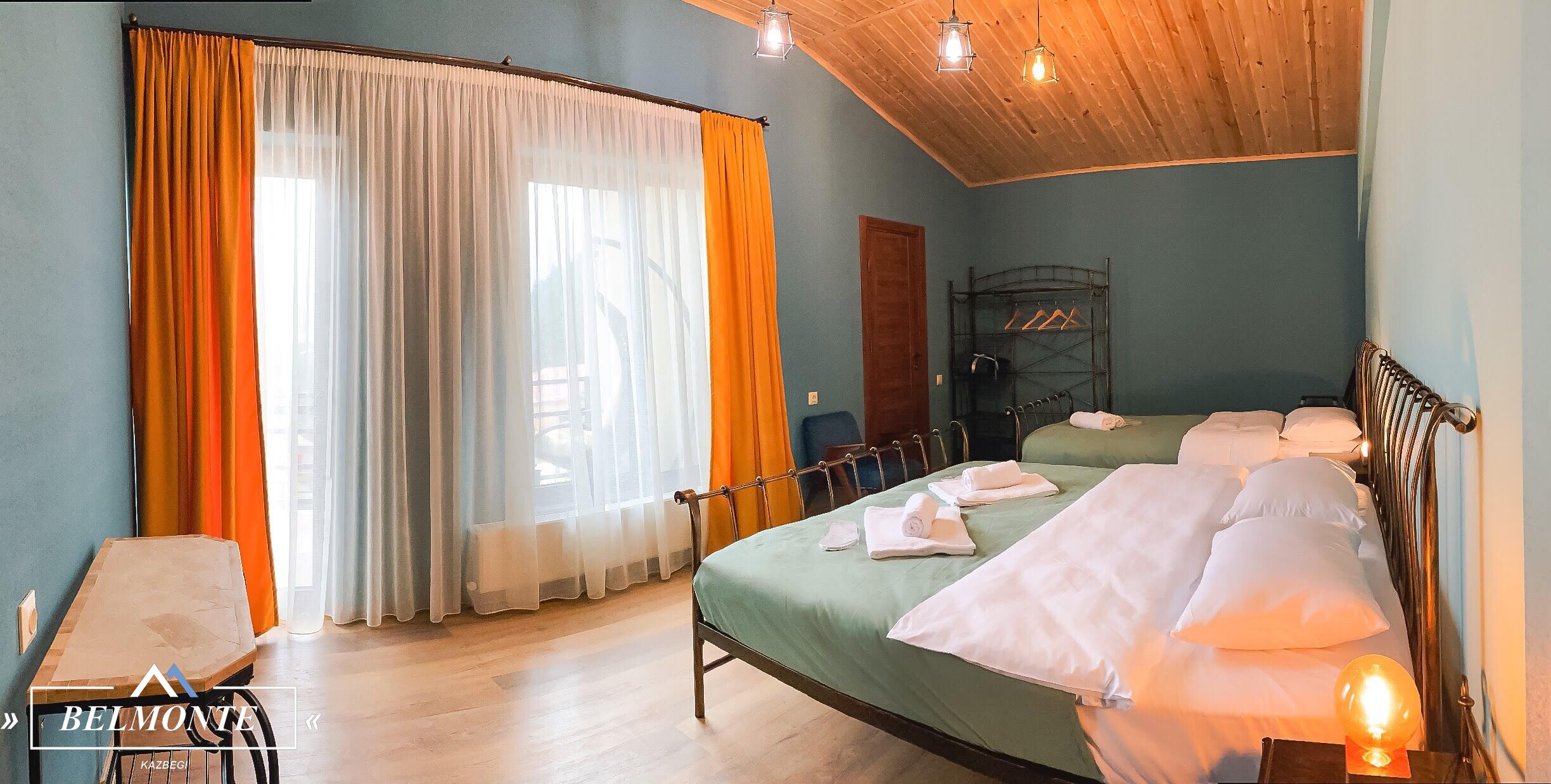 A bedroom with a bed, a bedside table, a chair, and a window with curtains.