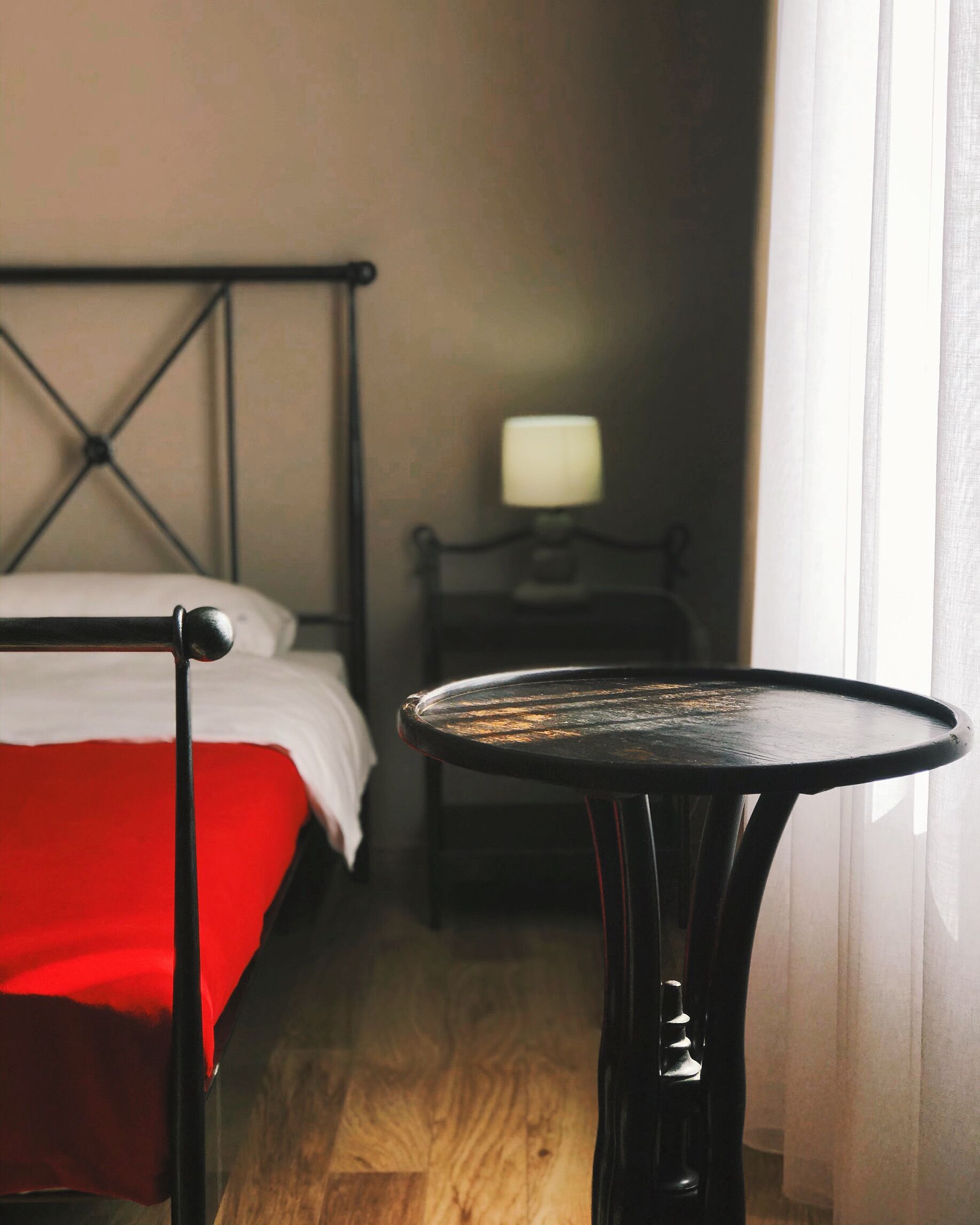 Une chambre d’hôtel avec un lit, une petite table et une table de chevet avec une lampe.