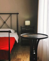 Habitación de hotel con cama, una mesita y una mesita de noche con lámpara.