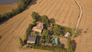 Vue aérienne d’une propriété rurale avec une maison entourée de champs, de panneaux solaires et d’une piscine.