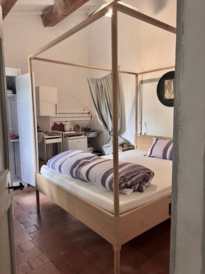 A four-poster bed with a canopy, a desk with a chair, a mirror, and a wardrobe. - La Fratta Art-House in Umbria. Double room (A) with garden view. (Marsciano)
