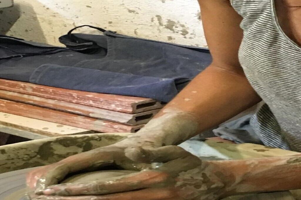 Eine Person arbeitet mit Ton, möglicherweise in einer Töpferei.