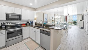 A modern kitchen with white cabinetry, stainless steel appliances, and a large island with a sink.
