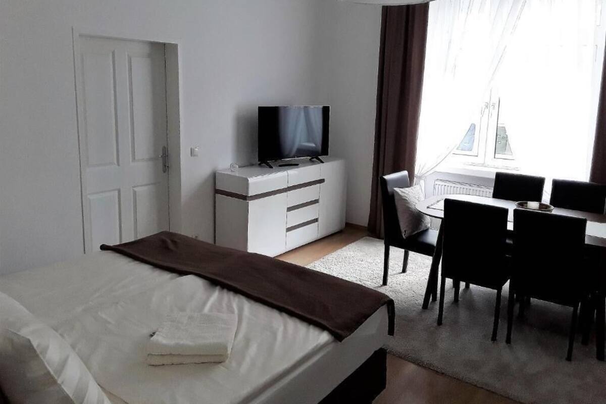 A hotel room with a bed, a desk, a chair, a television, and a window with curtains.