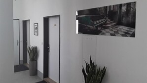 Um corredor com piano, obras de arte emolduradas e plantas em vasos.