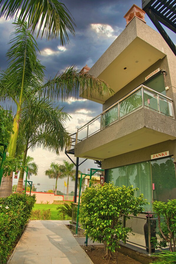Un edificio moderno con techo plano, un balcón y un escaparate con el nombre "JANKI".