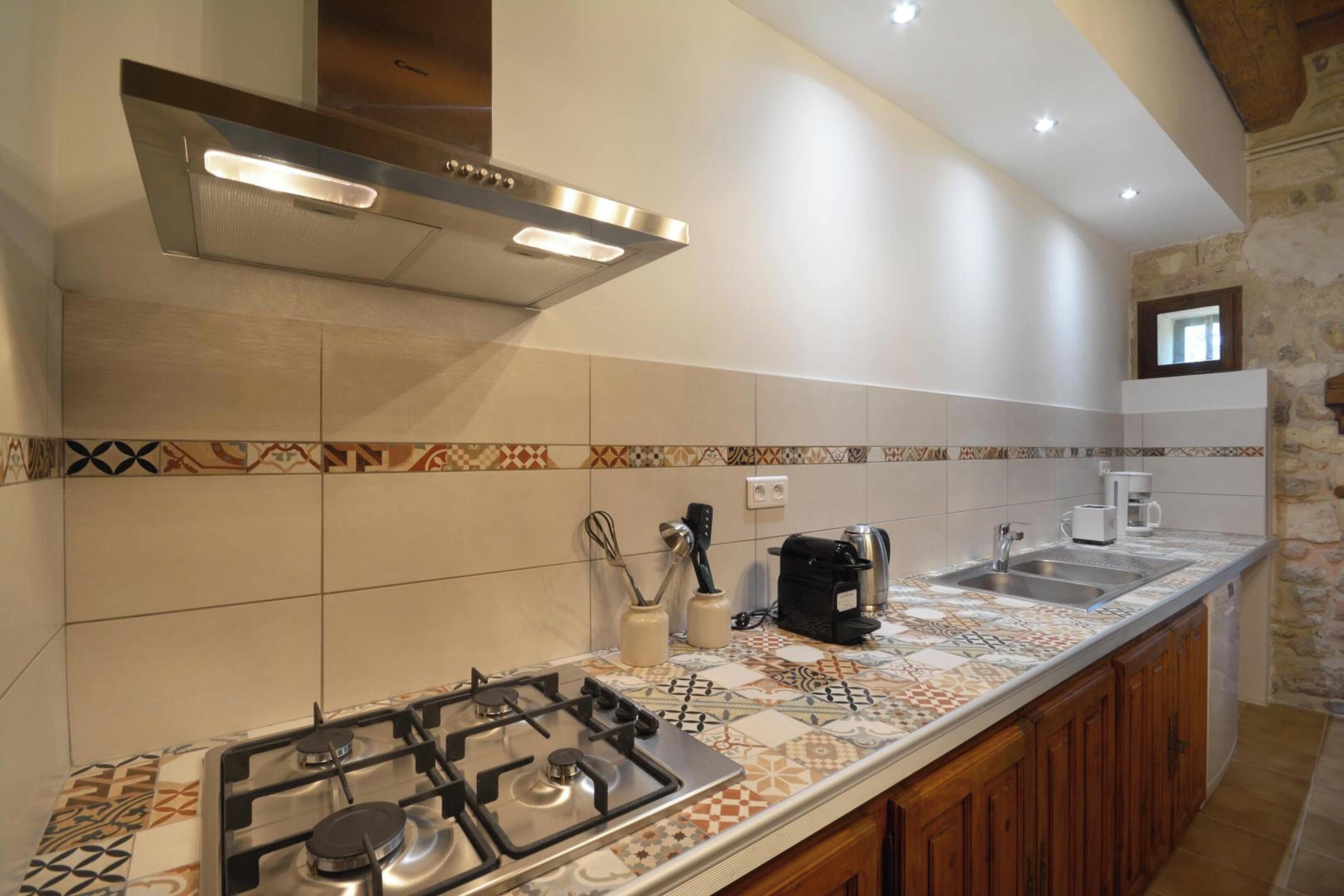 A kitchen with a gas stove, a coffee maker, and a sink.