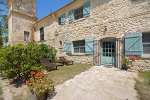 A stone building with a courtyard, featuring a gate, a small table, and potted plants. - Homerez - House near Saintes-Maries-de-la-Mer (Saintes-Maries-de-la-Mer)