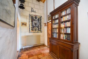 A hallway with a radiator, a wooden bookcase filled with books, and a framed artwork on the wall.
