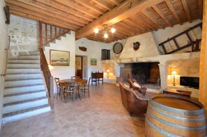 Un intérieur rustique avec un escalier en pierre, une table à manger en bois et une cheminée.