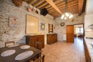 A rustic kitchen with stone walls, wooden furniture, and a tiled floor.