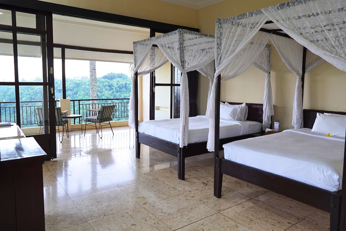 A hotel room with two beds, a balcony, and a view of the forest.