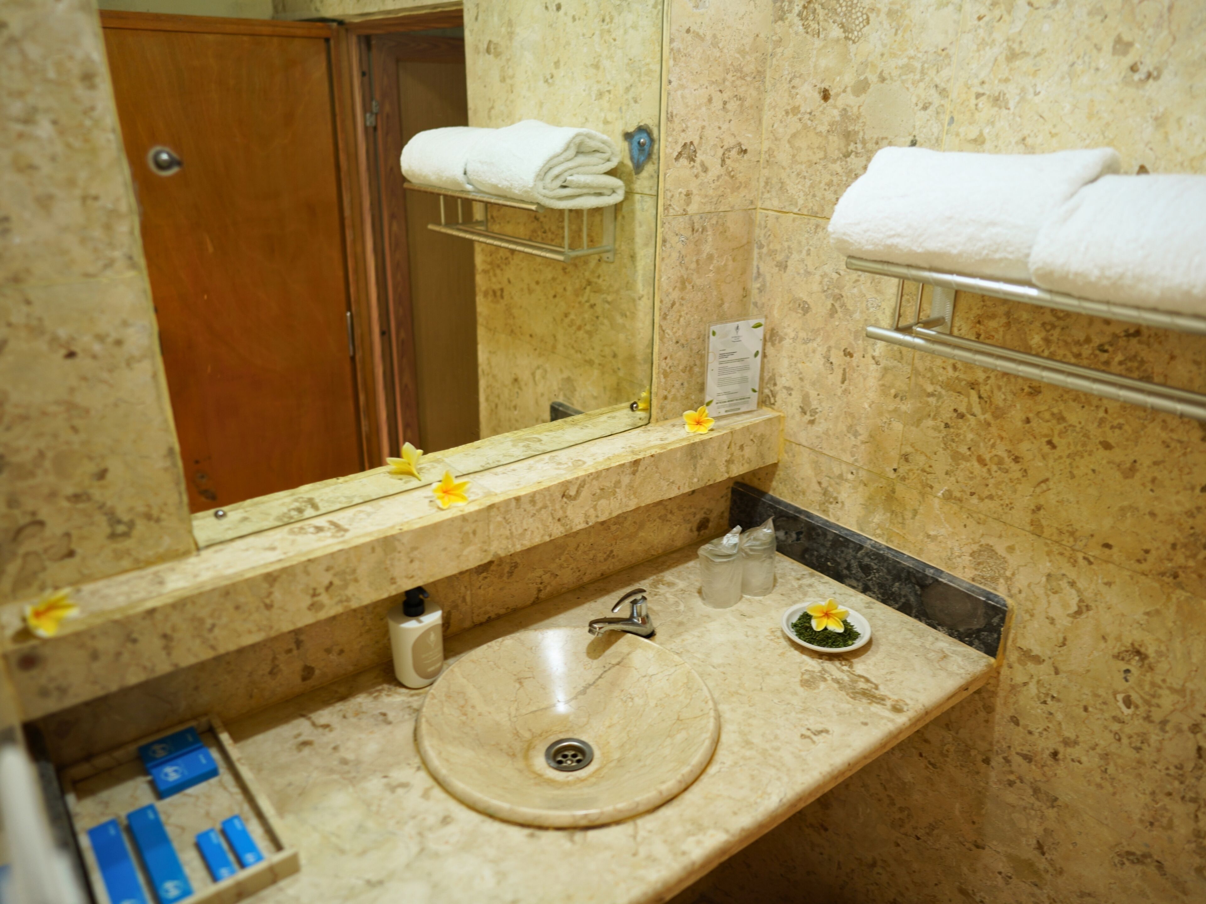 Une salle de bain avec un lavabo en marbre, un miroir, un porte-serviettes et une petite étagère contenant des articles de toilette.