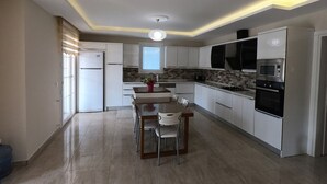 A modern kitchen with white cabinets, a central island with chairs, a built-in oven, and a microwave. - NEW LISTING!! BEAUTIFUL PRIVATE 5 BEDROOM VILLA RIGHT in CENTRE of DALYAN!!! (Dalyan Mahallesi / Ortaca)