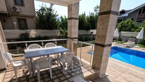 A covered outdoor area with a pool, a table with chairs, and a view of the surrounding buildings and greenery. - NEW LISTING!! BEAUTIFUL PRIVATE 5 BEDROOM VILLA RIGHT in CENTRE of DALYAN!!! (Dalyan Mahallesi / Ortaca)