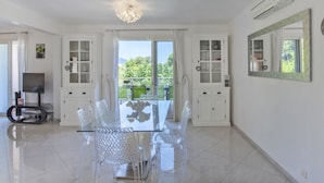 Una habitación amplia con una mesa de vidrio y sillas, armarios blancos y un espejo grande.
