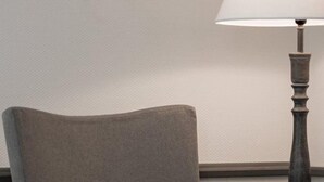 A chair with a teal pillow and a lamp with a white shade. - Hotel Klein Amsterdam (Friedrichstadt)