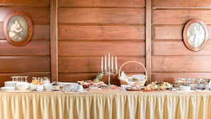 A buffet setup with various food items, a candelabra, and framed pictures on a wooden wall. - Hotel Klein Amsterdam (Friedrichstadt)