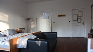 A bedroom with a bed, a sofa, a wardrobe, and a door with a window. - Boutique Pension Ahoi (Wesselburenerkoog)