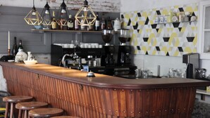 A bar area with a wooden counter, stools, and hanging pendant lights. - Boutique Pension Ahoi (Wesselburenerkoog)