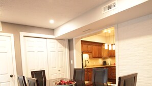 A dining area with a wooden table and chairs, a bowl of fruit, and a kitchen in the background. - Modern 3BR/ Close to Encore- Everett #2 (Everett)