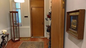 A hallway with a wooden door, a glass display cabinet, a bicycle, a rug, and a framed picture on the wall. - Il Genio del Porto - Mabbonath b&b (Palermo)