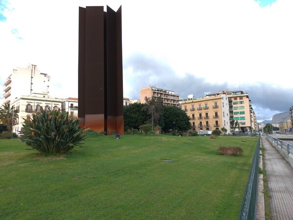 Una scultura moderna in un'area erbosa, con edifici sullo sfondo.
