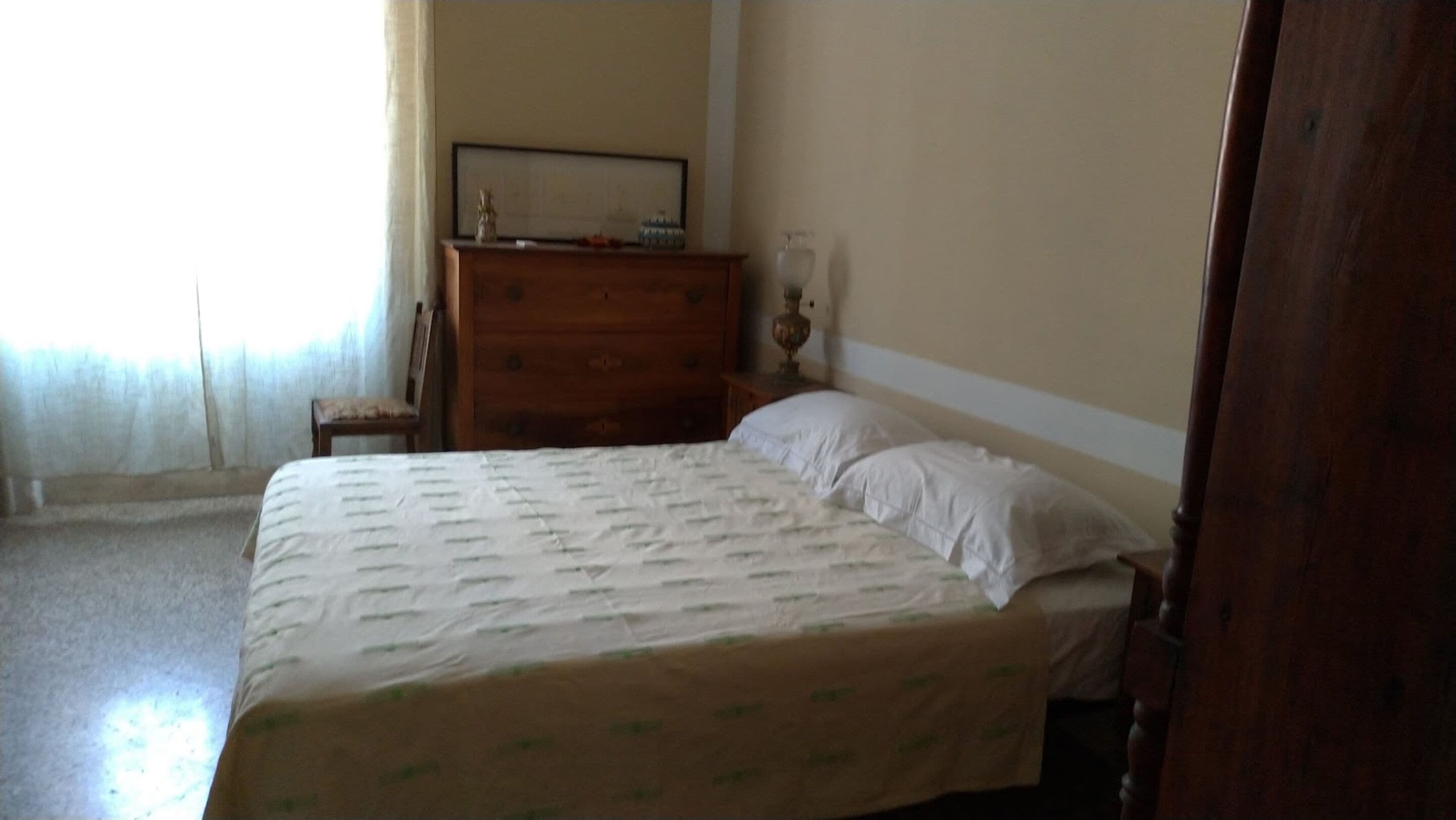 Een slaapkamer met een bed, een dressoir en een nachtkastje.