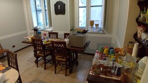 A dining area with a table set for four, chairs, a clock on the wall, and a window with blinds. - Il Genio del Porto - Mabbonath b&b (Palermo)