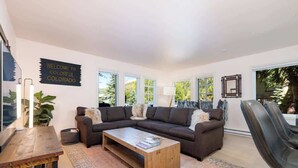 Een moderne woonkamer met een modulaire bank, een houten salontafel en een groot raam met uitzicht op groen.
