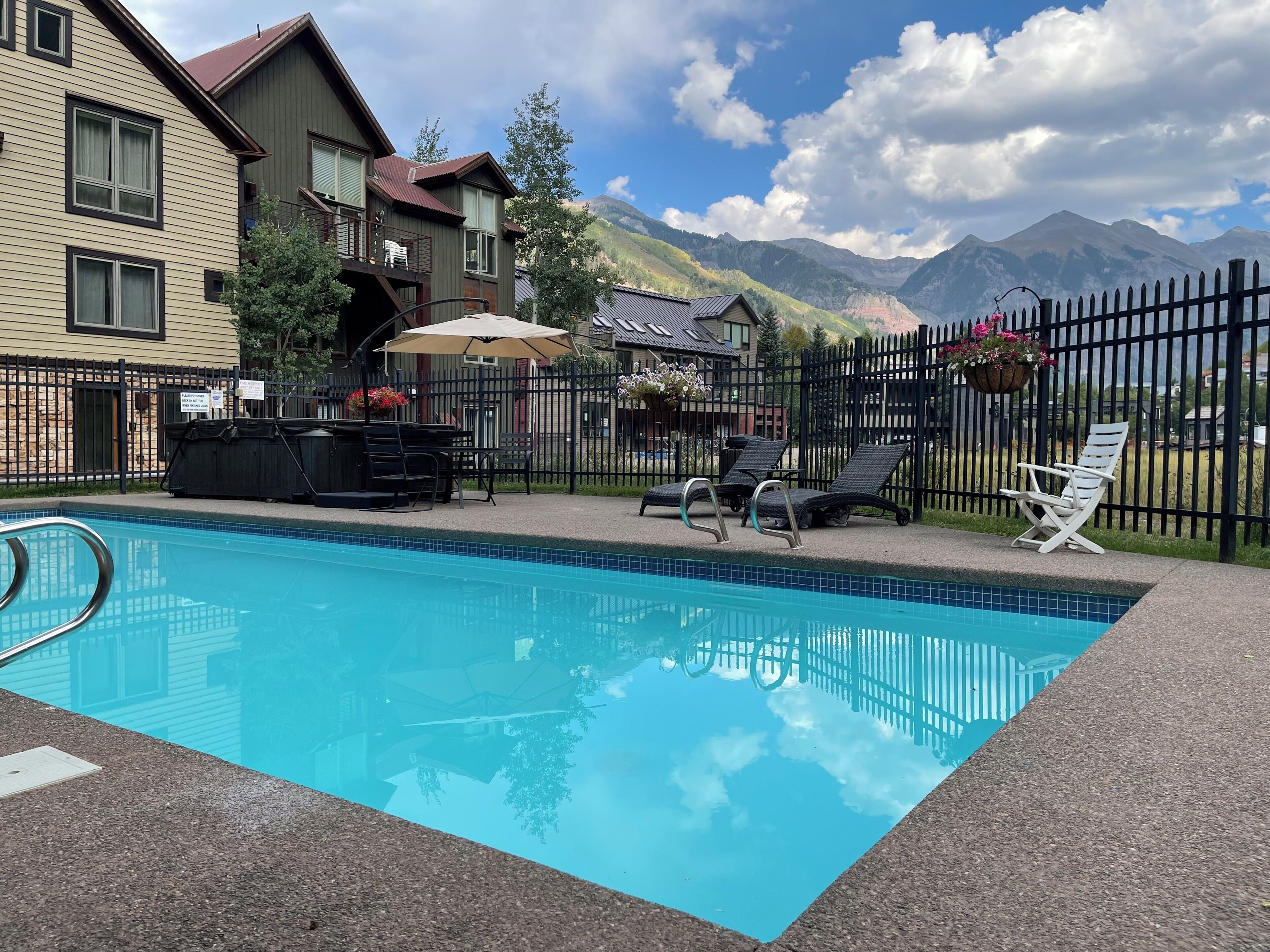 Ein Schwimmbad mit Liegestühlen, einem Grillplatz und Blick auf die Berge.