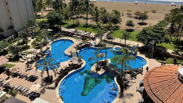 A resort with multiple swimming pools, a beach, and palm trees.