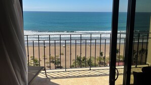 A balcony with a view of the beach and ocean.