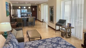 A modern living room with a sofa, coffee table, and a dining area with a kitchen in the background.