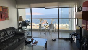 Un salon moderne avec un canapé en cuir, une table basse en verre et un balcon offrant une vue sur la mer.
