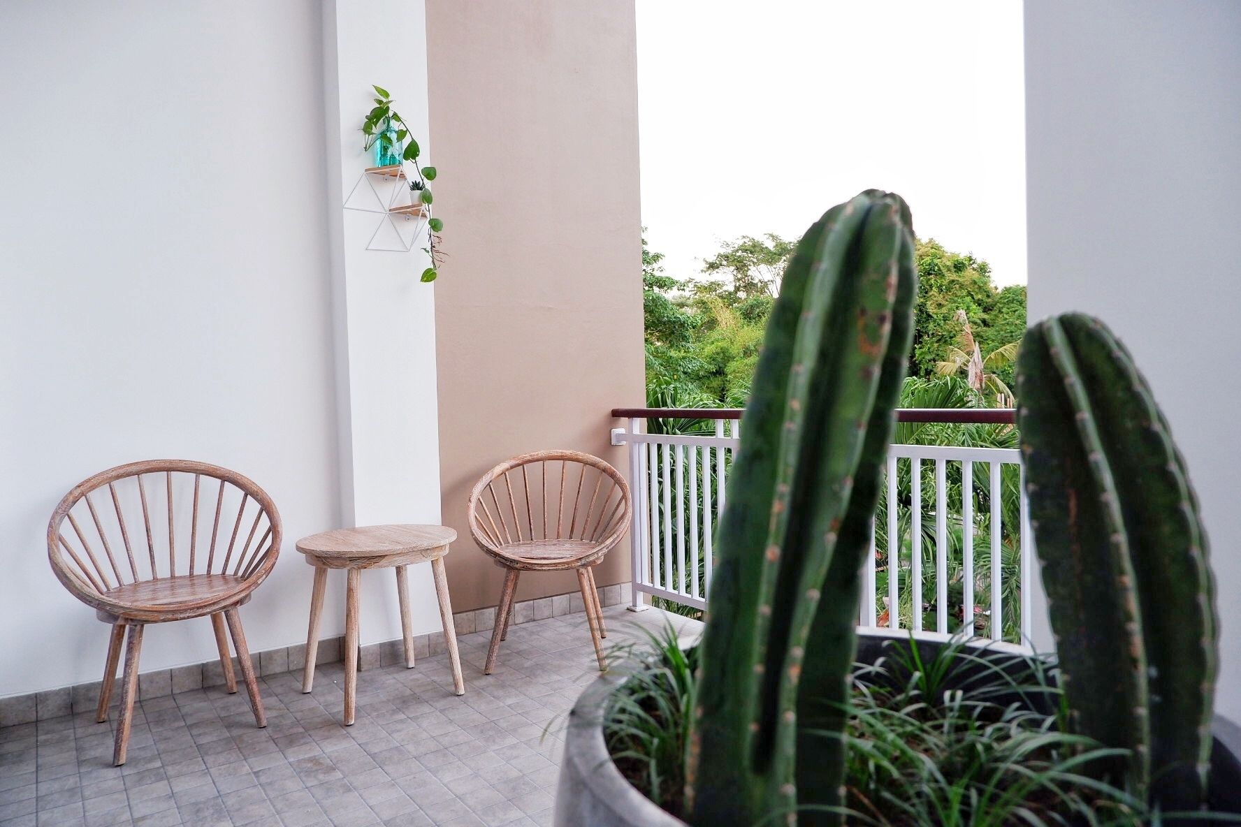 A balcony with two wicker chairs, a small table, and a potted cactus.