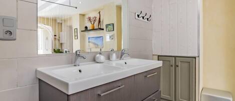 A modern bathroom with a double sink, dark cabinetry, and a large mirror.