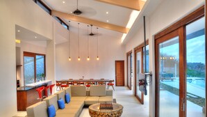 Un vaste espace de vie comprenant un canapé moderne, une table basse en bois et un coin repas avec des chaises rouges.